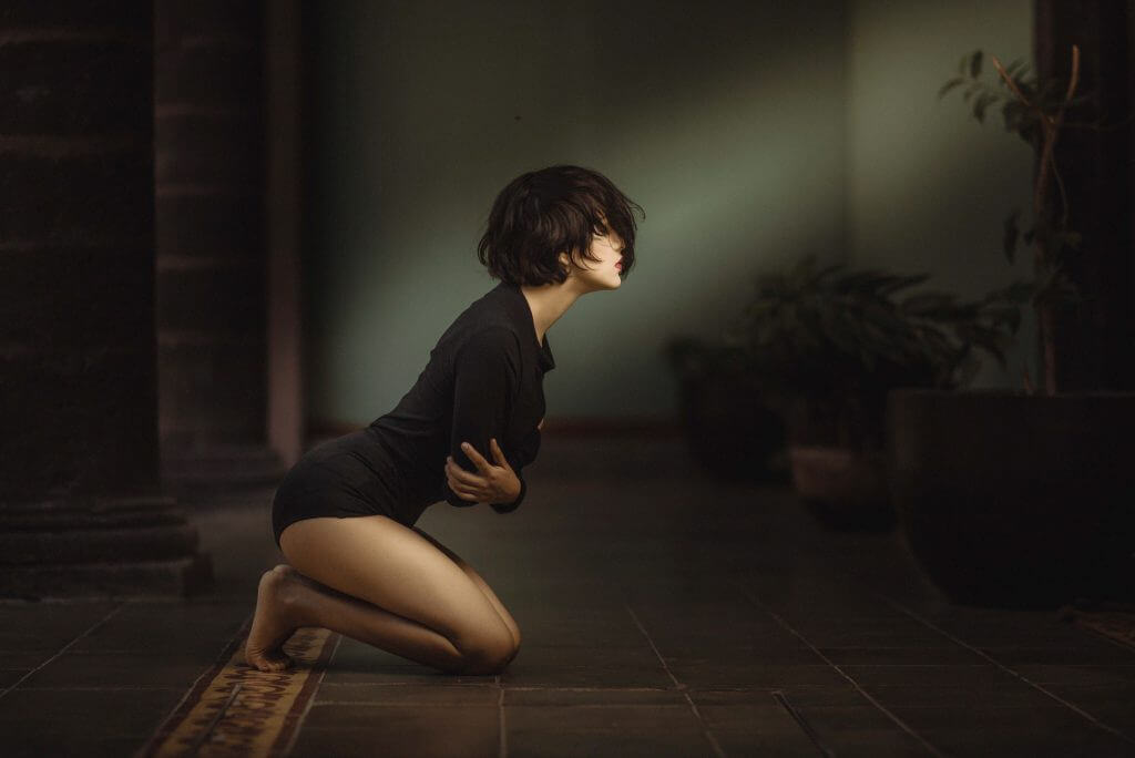 Woman kneeling on tiled floor looking up into light with hope