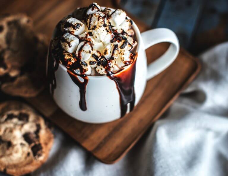 Make yourself a comforting cup of hot chocolate like this image of a white mug spilling over with dark hot chocolate and lathered in whipped cream while we discuss Gadolinium toxicity symptoms treatment