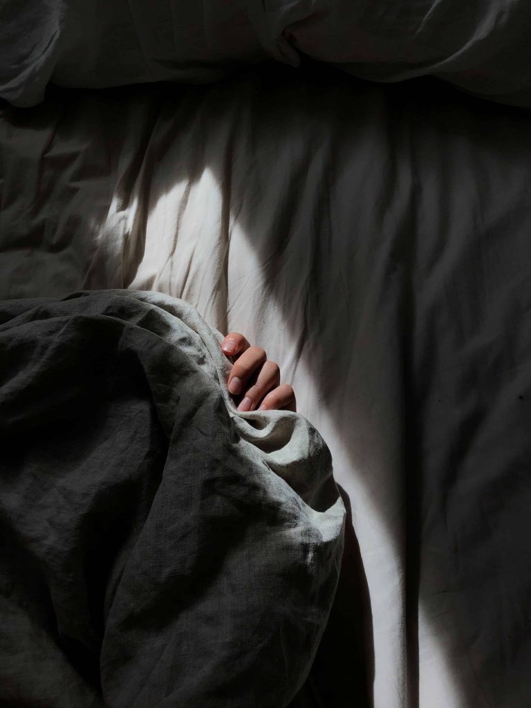Arm poking out from under the duvet in bed of a person with sleep anxiety